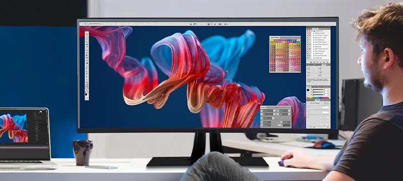 a man uses graphic design software on an ultrawide monitor